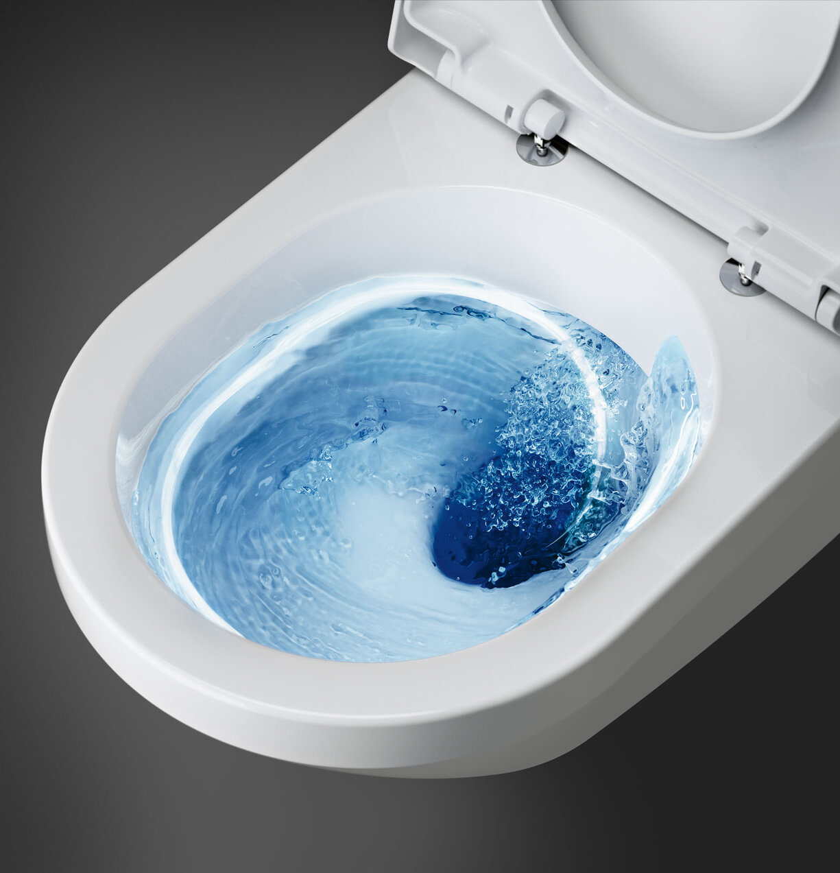 Et hvitt toalett med blått vann som virvler inni under spyling, sett ovenfra.