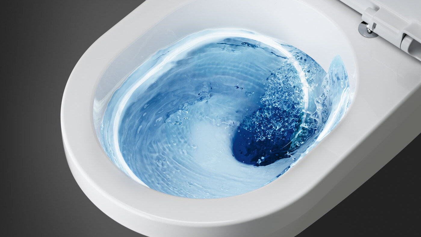 Valkoinen wc, jonka sisällä pyörii sinistä vettä huuhtelun aikana, ylhäältä katsottuna.