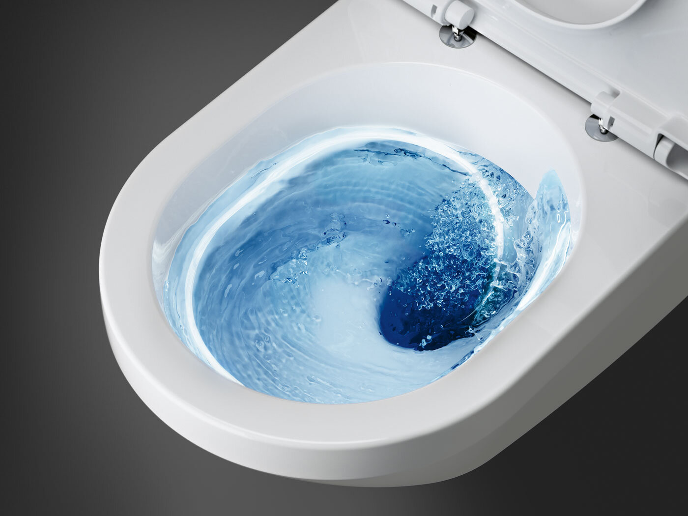 Valkoinen wc, jonka sisällä pyörii sinistä vettä huuhtelun aikana, ylhäältä katsottuna.