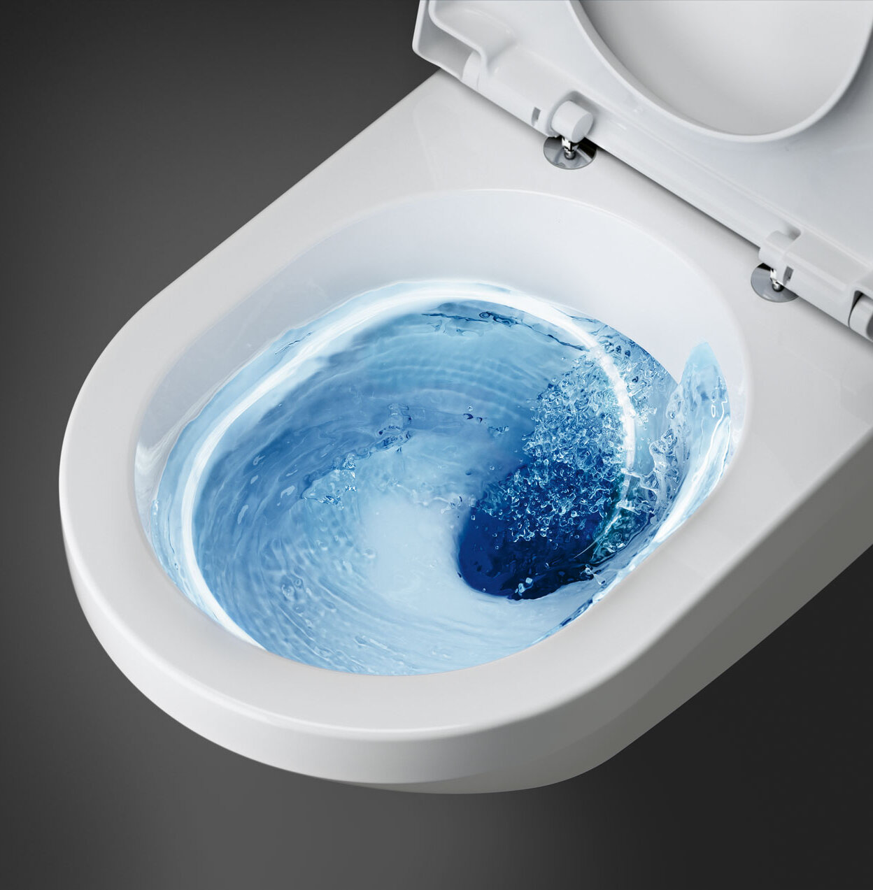 Valkoinen wc, jonka sisällä pyörii sinistä vettä huuhtelun aikana, ylhäältä katsottuna.