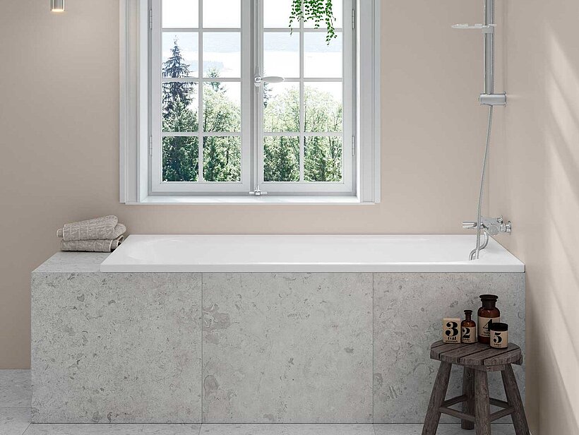 White built-in bathtub placed under a window.
