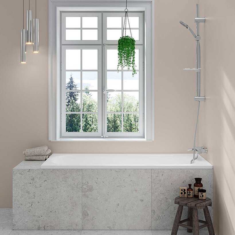 Vitt inbyggt badkar placerat alle ett fönster.