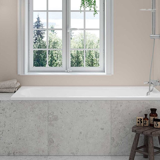 White built-in bathtub placed under a window.