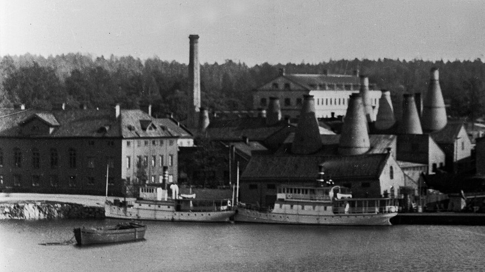 Gammelt fotografi af industribygninger med høje skorstene i Gustavsberg.