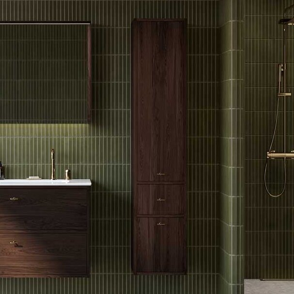 Vonios kambarys apstatytas tamsaus ąžuolo „Ducentic“ baldais – komoda ir aukšta spintelė – bei žalvariniais praustuvo maišytuvais ir dušo kabina. Ant sienų – žalios plytelės, o langams – medinės žaliuzės.