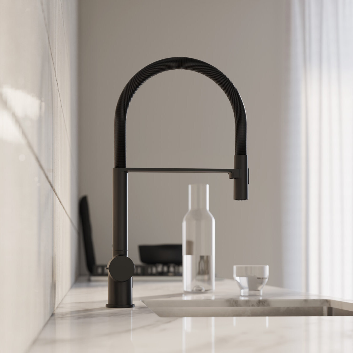 Modern svart Esstetic-köksblandare på en marmorbänkskiva. Glasflaskor och ett handfat i närheten, upplyst av naturligt ljus.