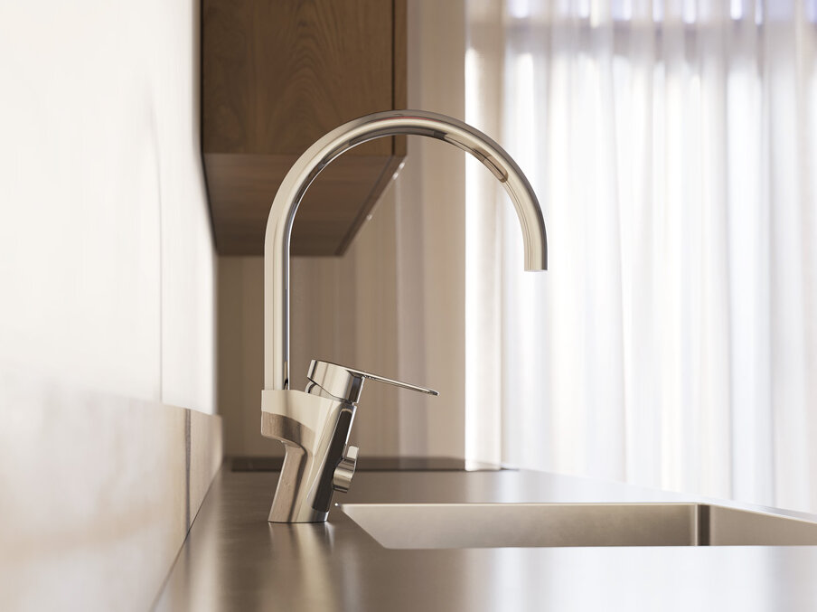Närbild på en modern köksdiskbänk med en hög köksblandare i krom och naturligt ljus som kommer in genom tunna gardiner i bakgrunden.