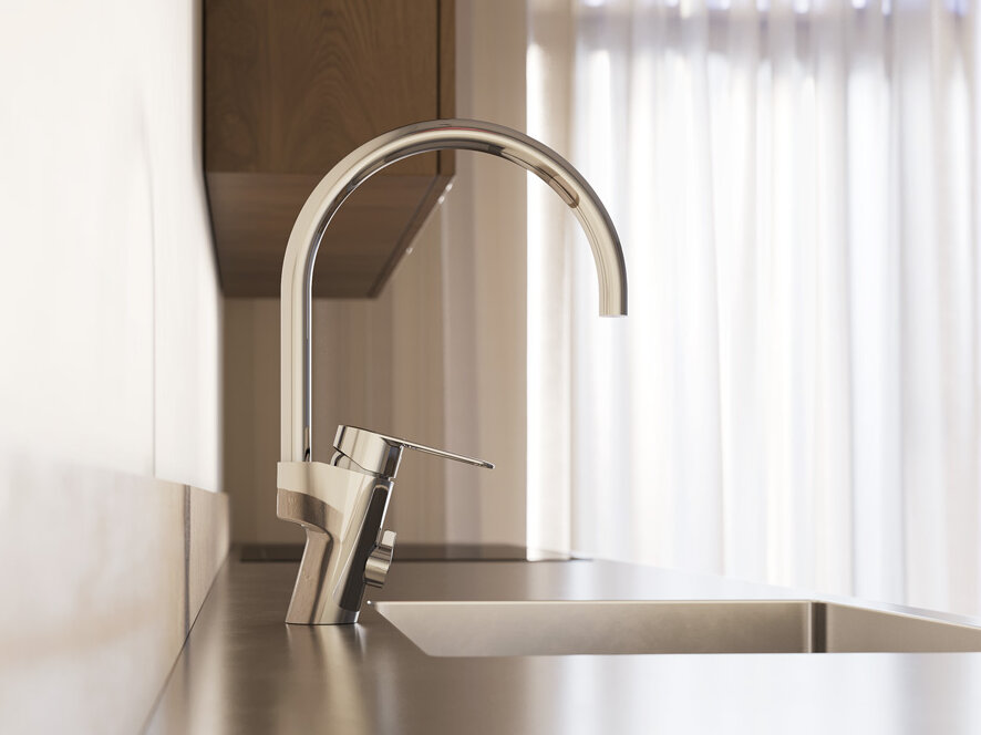 Närbild på en modern köksdiskbänk med en hög köksblandare i krom och naturligt ljus som kommer in genom tunna gardiner i bakgrunden.
