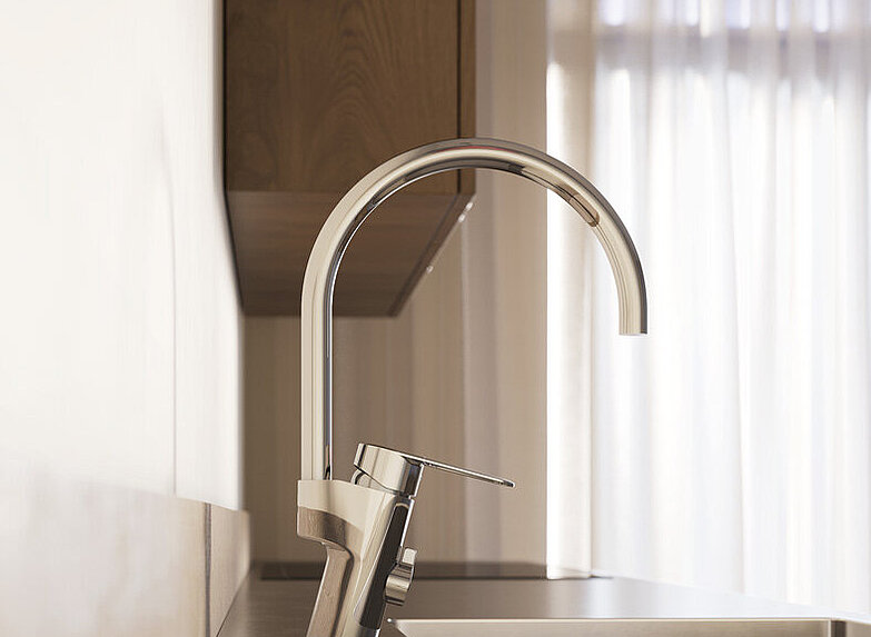 Šiuolaikinės virtuvės kriauklės su aukštu chromuotu virtuvės maišytuvu ir natūralios šviesos, sklindančios pro plonas užuolaidas fone, stambus planas.