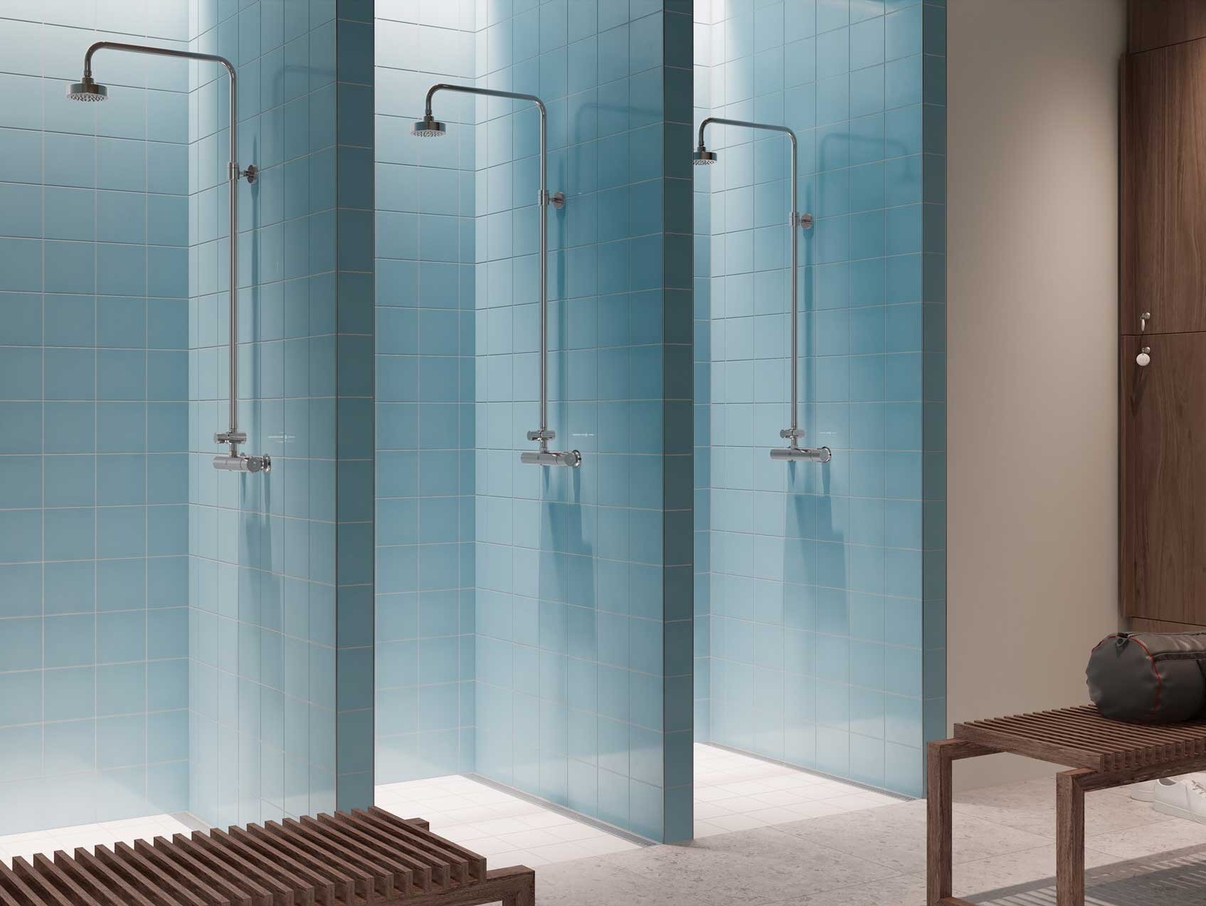 Tre brusekabiner med glasvægge og moderne armaturer i et minimalistisk omklædningsrumsmiljø i blåt og beige.