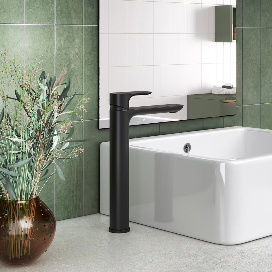 A modern bathroom sink with a tall black faucet, next to a brown vase on green tiles, offers elegant bathroom inspiration..