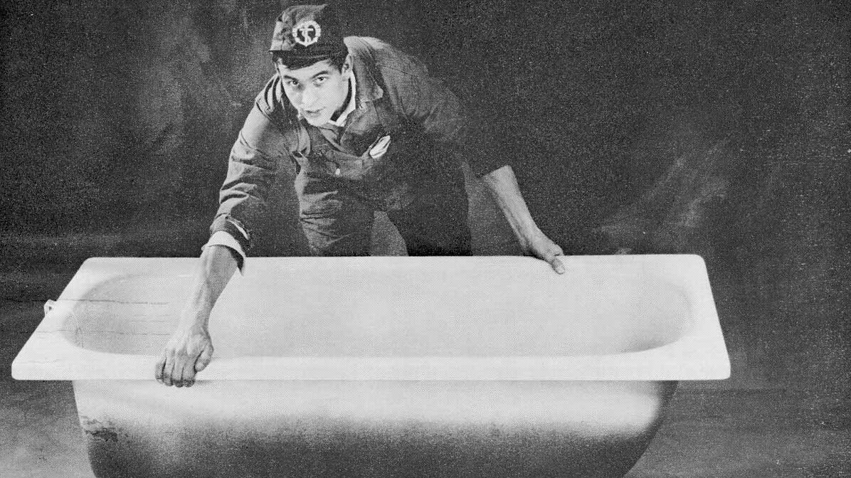 A man in a Gustavsberg uniform inspects a freestanding bathtub.