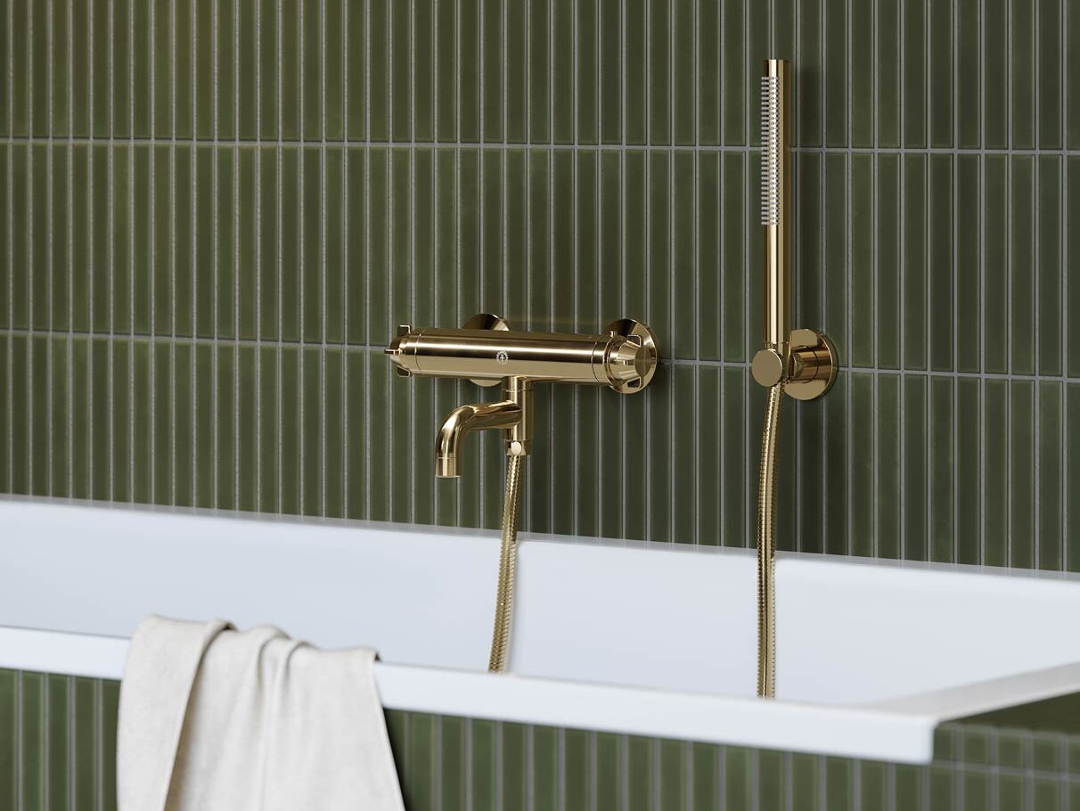 Žalvarinis „Ducentic“ vonios maišytuvas ant žaliomis plytelėmis išklijuotos sienos.