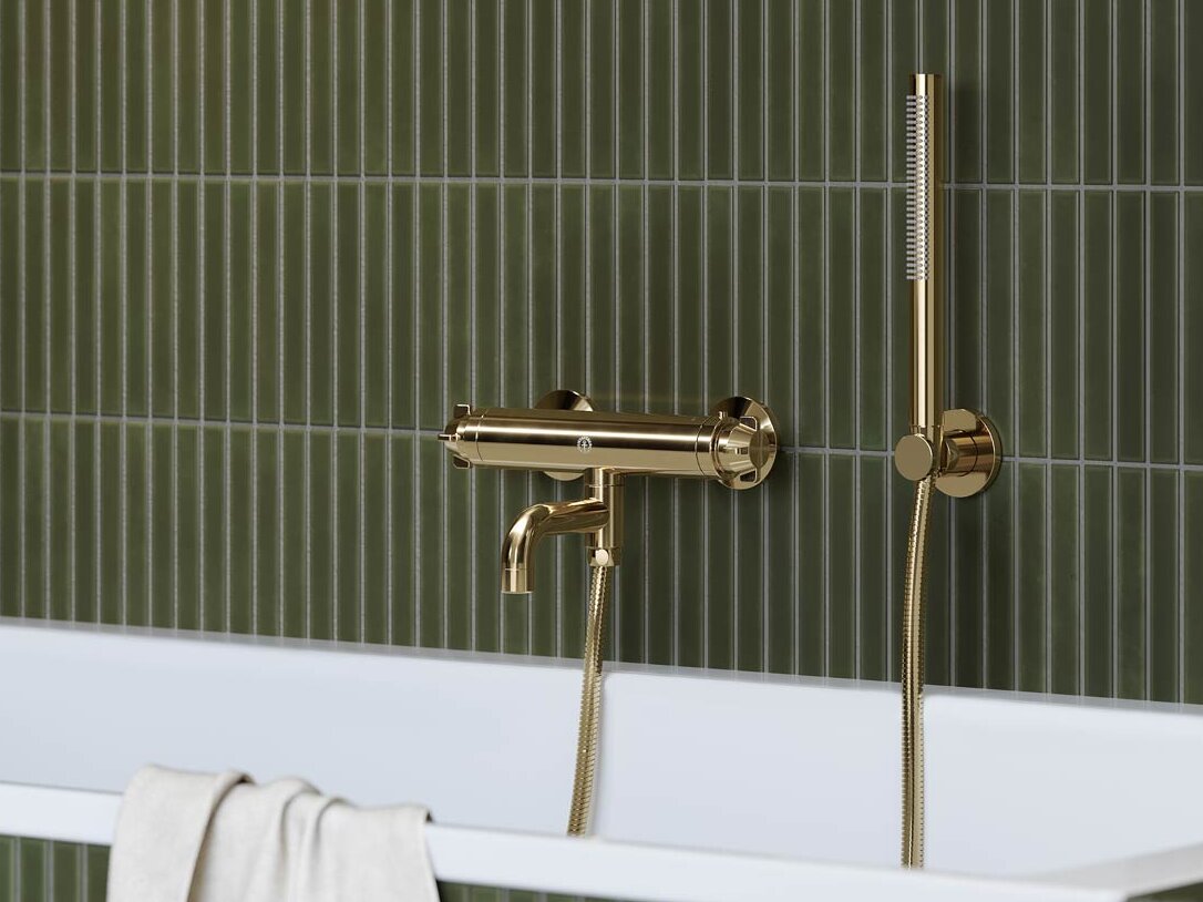 Messingistä valmistettu Ducentic-kylpyhuonehana vihreällä laatoitettulla seinällä.