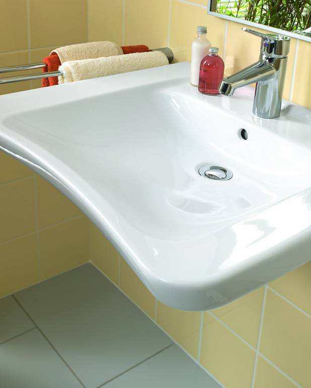 Håndvask 5G7860 - hjælpemiddel, boltmontering 60 cm - Tilpasset kørestolsbrugere med fladt bassin
Fronten buer indad, så brugeren kan komme helt tæt ind til vasken 
Glat underside med gribekanter og god benplads