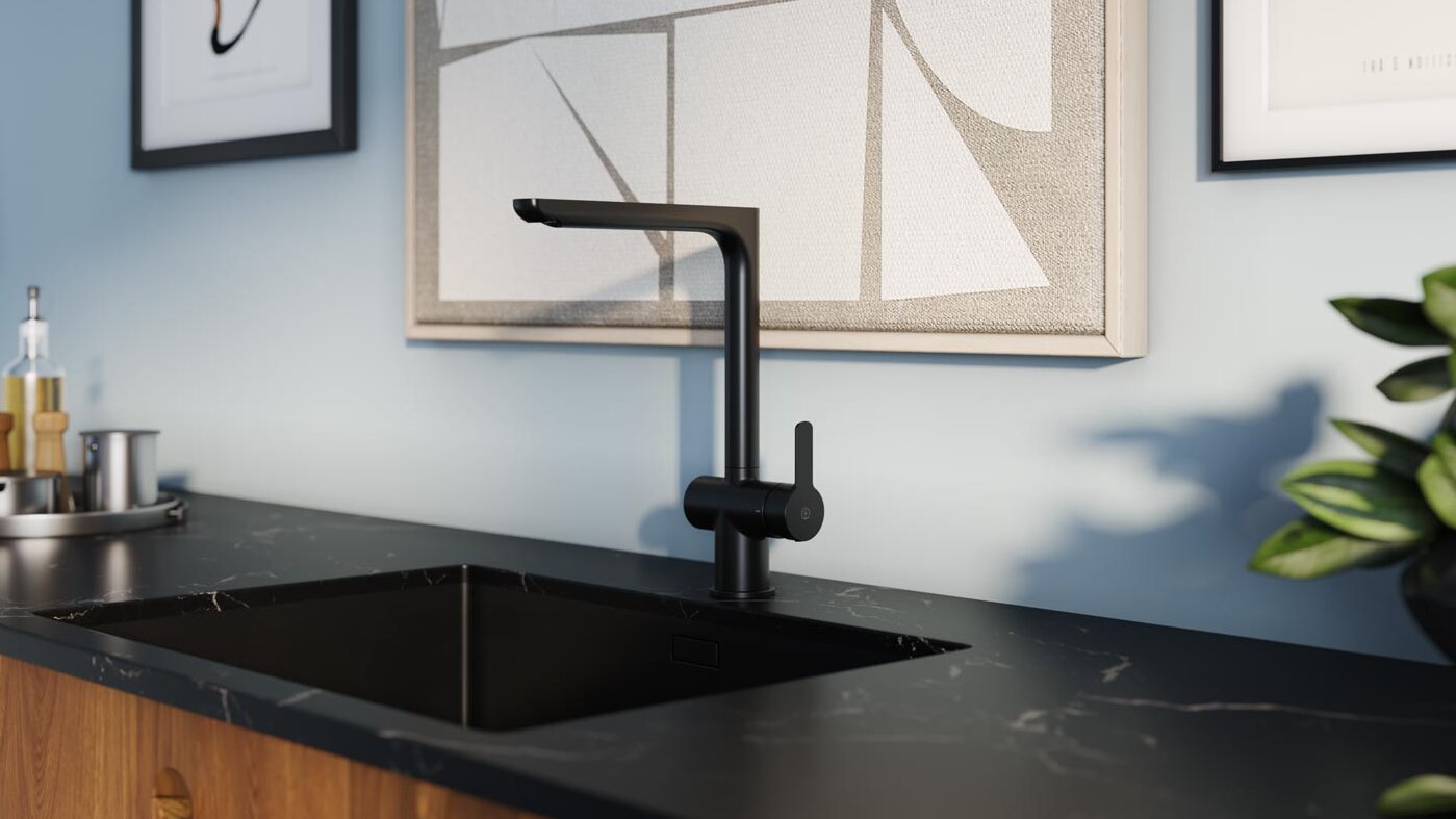 Modern kitchen sink with a sleek Gustavsberg black faucet featuring smart functions on a marble countertop, framed art, and a plant in the background.