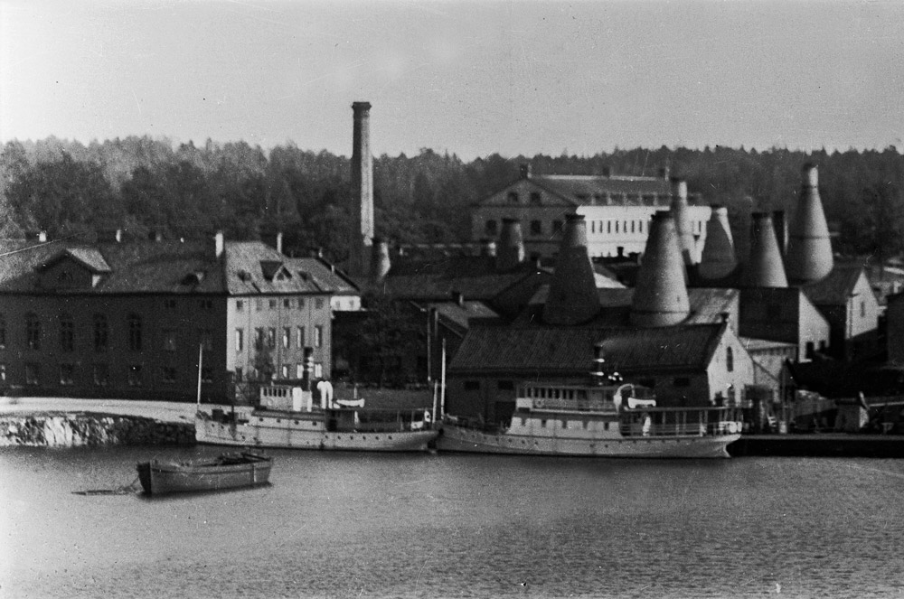 Gammelt fotografi av industribygninger med høye skorsteiner i Gustavsberg.