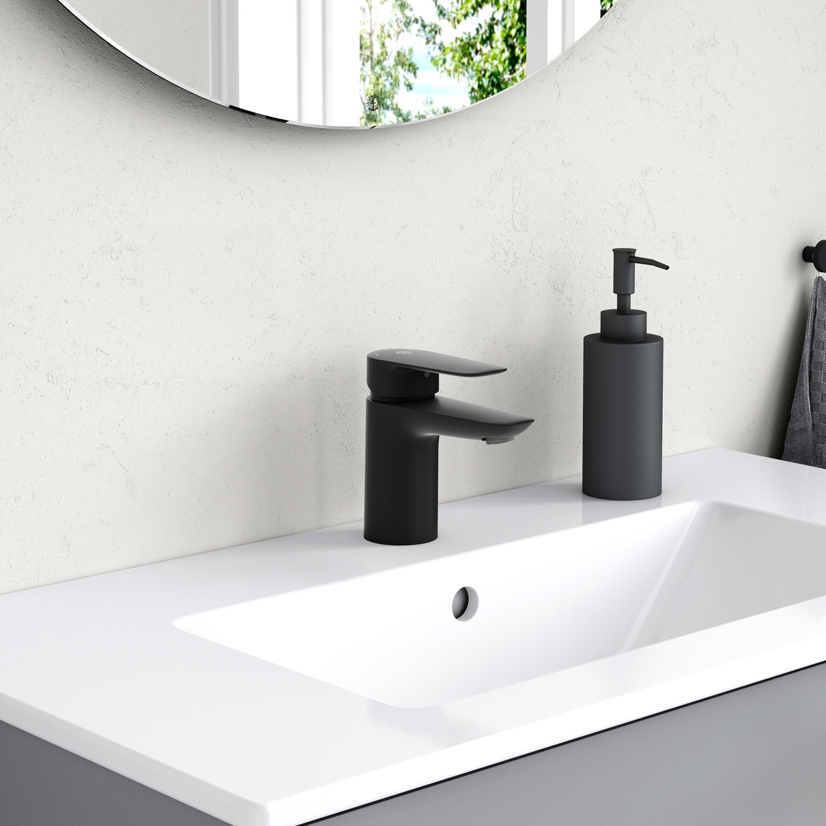 Hvit baderomsvask med svart blandebatteri og matchende såpedispenser på en hvit benkeplate under et rundt speil.