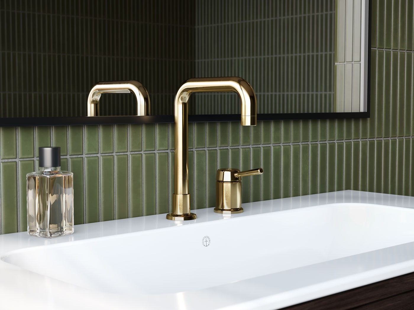 Et forkrommet servantbatteri, en såpedispenser og en hvit servant foran en grønn flislagt vegg og et stort speil.