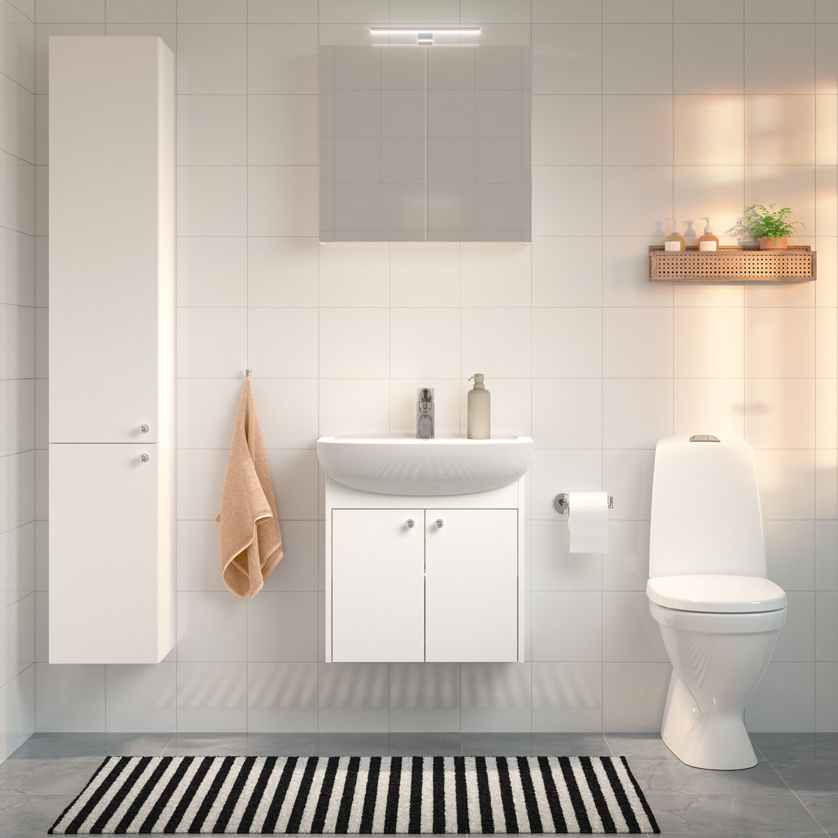 Bad med hvite armaturer, vegghengt vask, hvite baderomsmøbler, stripete teppe og et håndkle hengende på veggen.