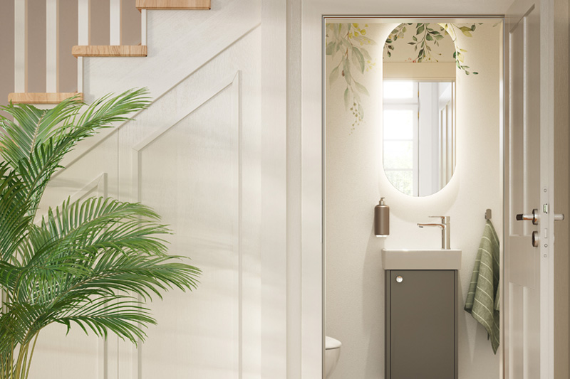 Under-staircase bathroom solutions with a wall-mounted sink, oval mirror, potted plant, and natural light from an upper window.